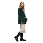 So and Ro black leather knee-high boots with chunky sole worn by a woman in a green blazer and cream dress.
